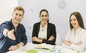 Trois apprenants en réunion, un homme tant la main à une personne