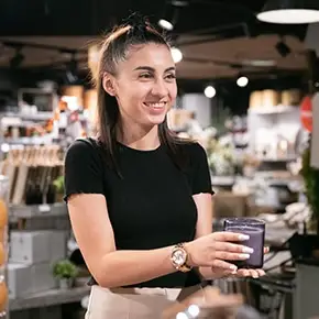 étudiante dans un magasin d'objet tendant une bougie à un client