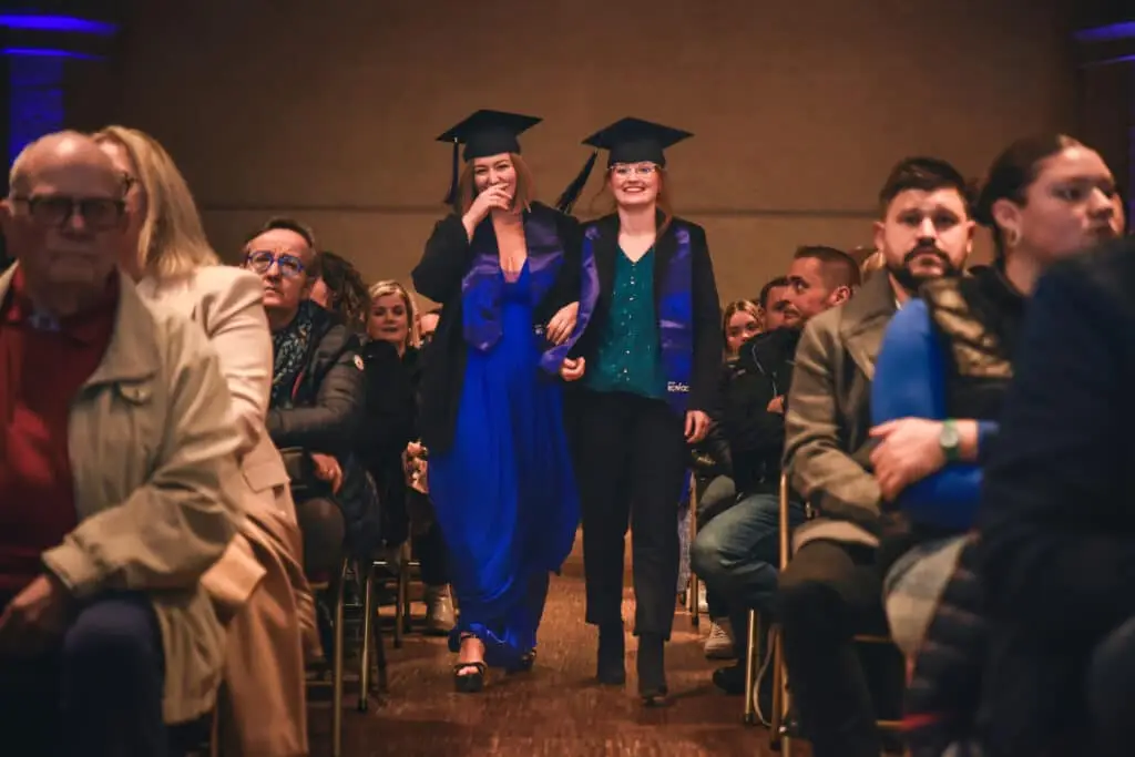 Étudiantes diplômées d'Ecofac marchant dans l'allée pour se rendre sur la scène de la remise de diplômes.