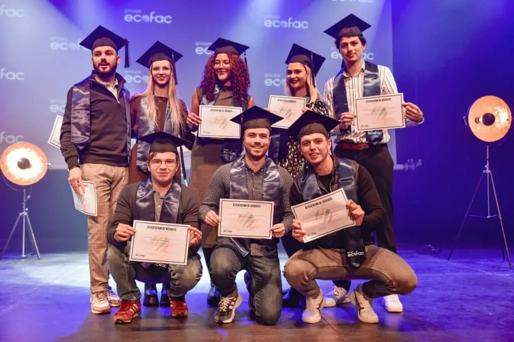 Photo de promo sur la scène de la remise des diplômes, avec les étudiants d'Ecofac montrant leurs diplômes.