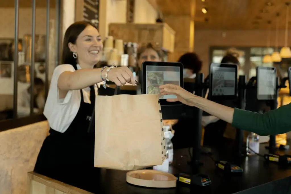 une jeune femme donne un sac à une cliente