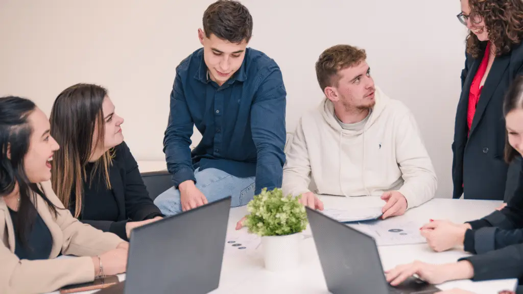 5 étudiants échangent autour d'une table lors d'un projet de groupe