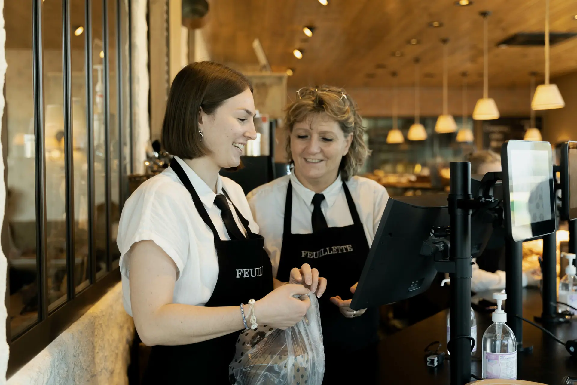 Photo d'une étudiante Ecofac en alternance dans une boulangerie avec sa responsable à la caisse de la boulangerie.