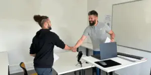 un formateur et un apprenant Ecofac Academy se serrent la main avant d'enregistrer un entretien de vente
