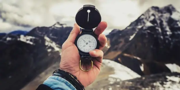 un homme qui tient une boussole pour représenter l'orientation