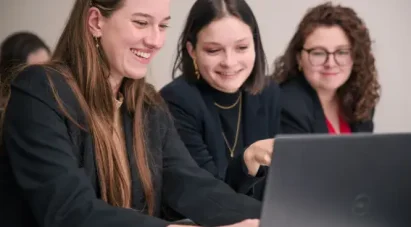 3 étudiantes Ecofac souriantes qui échangent face à leur ordinateur